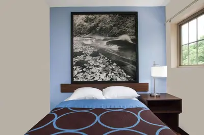 a bedroom with a bed with a painting on the wall at Super 8 by Wyndham Oneonta/Cooperstown in Oneonta