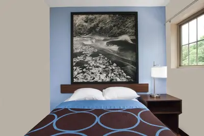 a bedroom with a bed with a painting on the wall at Super 8 by Wyndham Oneonta/Cooperstown in Oneonta