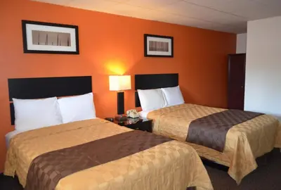 two beds in a hotel room with orange walls at Enfield Inn in Enfield