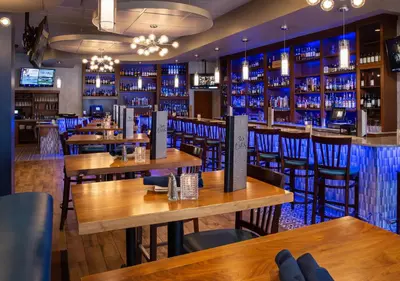 a restaurant with wooden tables and chairs and a bar at Hilton Garden Inn Clifton Park in Clifton Park