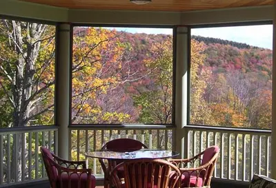 a screened in porch with a table and chairs at Breezy Hill Inn in Fleischmanns