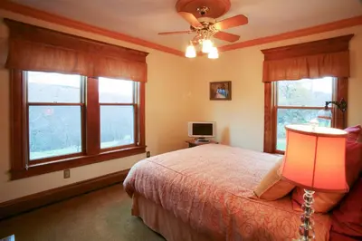 a bedroom with a bed with a ceiling fan and windows at Breezy Hill Inn in Fleischmanns