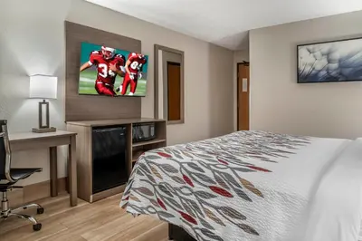a hotel room with a bed and a flat screen tv at Red Roof Inn Queensbury in Queensbury