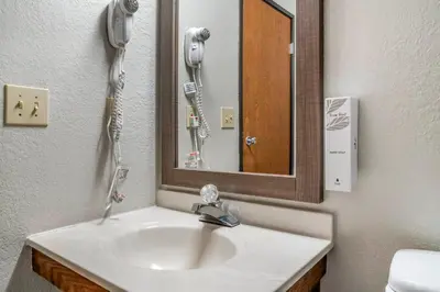 a bathroom with a sink with a mirror and a phone at Red Roof Inn Queensbury in Queensbury