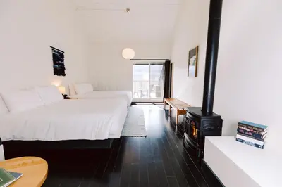 a hotel room with two beds and a fireplace at Scribner's Catskill Lodge, a Member of Design Hotels in Hunter