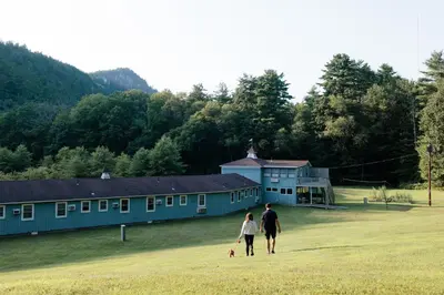 a man and woman walking a dog in front of a house at The Little Lion in Great Barrington