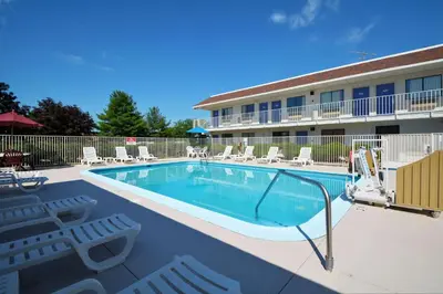 a swimming pool in front of a hotel with chairs at Motel 6-Windsor Locks, CT - Hartford in Windsor Locks