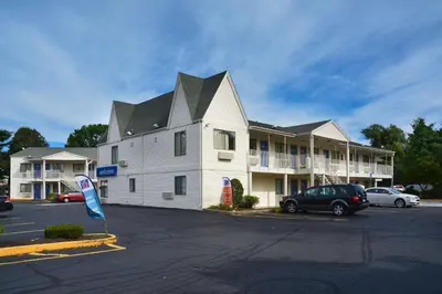 a large white building with a flag in a parking lot at Motel 6-Southington, CT - Hartford in Southington