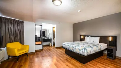 a hotel room with a bed and a yellow chair at Motel 6-Wethersfield, CT - Hartford in Wethersfield