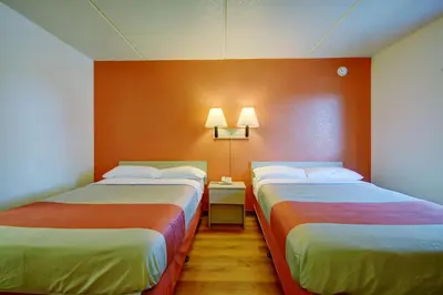 two beds in a room with orange walls at Motel 6-Chicopee, MA - Springfield in Chicopee