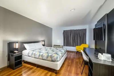 a bedroom with a bed and a desk with a yellow chair at Motel 6-Branford, CT - New Haven in Branford