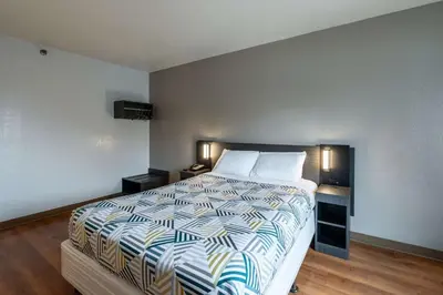 a bedroom with a large bed with a striped comforter at Motel 6-Branford, CT - New Haven in Branford