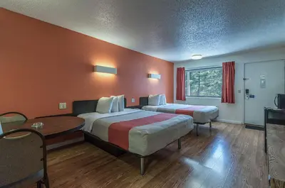 a hotel room with two beds and a table at MOTEL 6 - Albany, NY - Airport in Albany