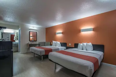 two beds in a hotel room with orange walls at MOTEL 6 - Albany, NY - Airport in Albany