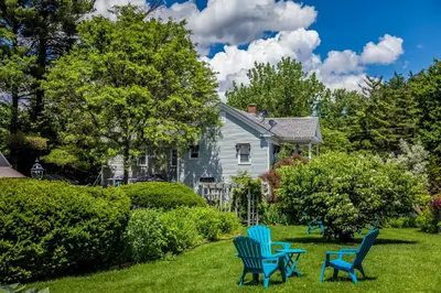 two blue chairs sitting in the grass in front of a house at Maple Terrace Motel in Williamstown