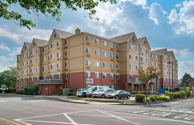 a large building with cars parked in a parking lot at Extended Stay America Suites - Secaucus - New York City Area in Secaucus