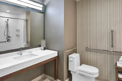 a bathroom with a sink and a toilet and a mirror at Courtyard by Marriott Albany Troy/Waterfront in Troy