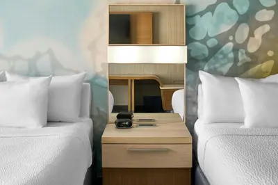 two beds with white pillows and a nightstand between them at Courtyard by Marriott Albany Troy/Waterfront in Troy