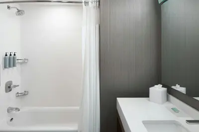 a bathroom with a shower and a white sink at Courtyard by Marriott Albany Troy/Waterfront in Troy