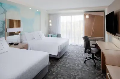 a hotel room with two beds and a desk and a television at Courtyard by Marriott Albany Troy/Waterfront in Troy
