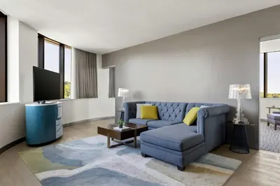 a living room with a blue couch and a tv at The MC, Autograph Collection in Montclair
