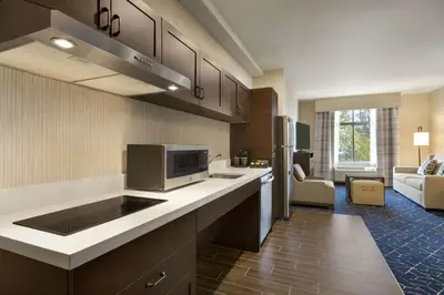 a kitchen with a counter and a living room at Homewood Suites by Hilton Albany Crossgates Mall in Albany