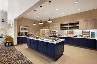 a large kitchen with blue cabinets and a counter at Homewood Suites by Hilton Albany Crossgates Mall in Albany
