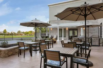 a patio with tables and chairs and umbrellas at Tru by Hilton Albany Crossgates Mall in Albany