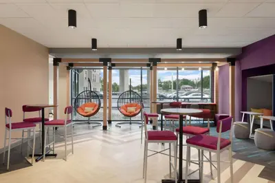 a bar with red chairs and tables in a room with windows at Tru by Hilton Albany Crossgates Mall in Albany