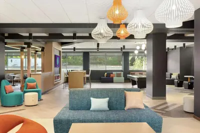 a lobby with a couch and tables and chairs at Tru by Hilton Albany Crossgates Mall in Albany
