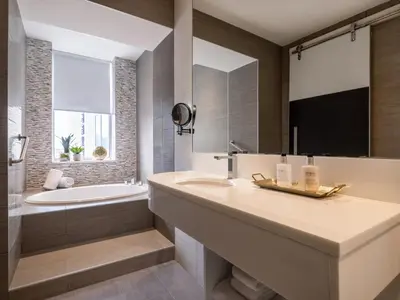 a bathroom with a sink and a bath tub and a tubermott at voco Fiorello - LaGuardia Airport by IHG in Queens