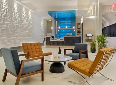 a lobby of a hotel with chairs and a table at voco Fiorello - LaGuardia Airport by IHG in Queens