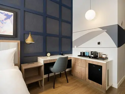 a bedroom with a bed and a desk with a chair at voco Fiorello - LaGuardia Airport by IHG in Queens