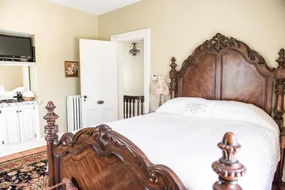 a bedroom with a large wooden bed with white sheets at The Bevin House B&B in East Hampton