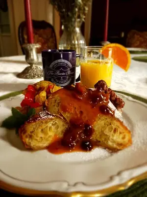a plate of food with bread and fruit and a glass of orange juice at The Bevin House B&B in East Hampton
