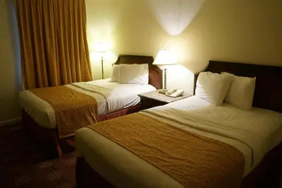 two beds in a hotel room with two lamps at Waterford Inn in Waterford