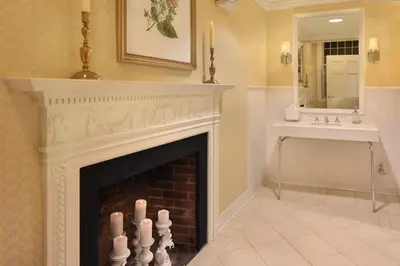 a fireplace in a bathroom with a sink and a mirror at Inn on Boltwood in Amherst