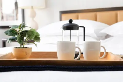 a tray with two coffee mugs and a lamp on a bed at The Stamford Hotel in Stamford