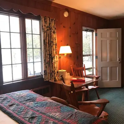 a bedroom with a table and chairs and windows at The 1896 House Country Inn - Brookside & Pondside in Williamstown