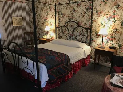 a bedroom with a canopy bed with floral wallpaper at The 1896 House Country Inn - Brookside & Pondside in Williamstown