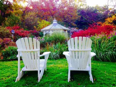 two white chairs in a garden with a gazebo at The 1896 House Country Inn - Brookside & Pondside in Williamstown