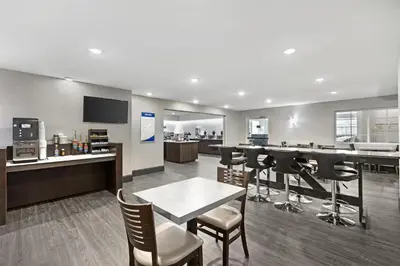 a lobby with a bar with stools and a kitchen at Best Western Cooperstown in Cooperstown