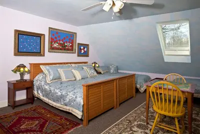 a bedroom with a bed and a desk and a ceiling fan at Beds on Clouds in Windham