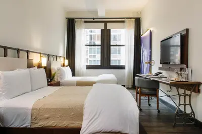 a hotel room with two beds and a desk at Refinery Hotel - New York in New York