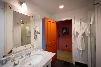 a bathroom with a sink and a robe hanging on a door at The Porches Inn at Mass MoCA in North Adams