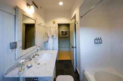 a white bathroom with a sink and a tub and a tubermott at The Porches Inn at Mass MoCA in North Adams