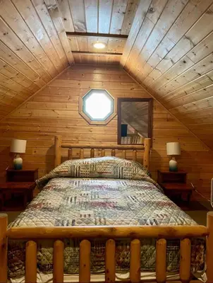 a bedroom with a bed in a wooden cabin at The Elms Waterfront Cottages in Lake Luzerne