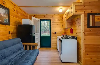 a kitchen and living room with a couch and a refrigerator at The Elms Waterfront Cottages in Lake Luzerne