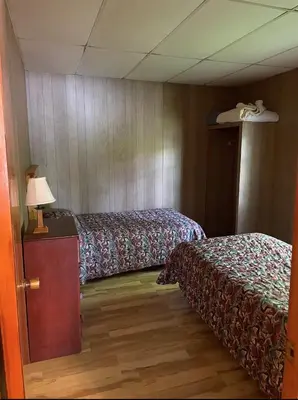 a room with two beds and a lamp on a table at The Elms Waterfront Cottages in Lake Luzerne