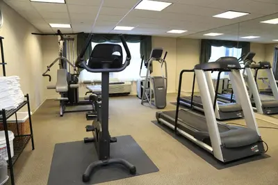 a gym with several tread machines in a room at Inn at Middletown in Middletown